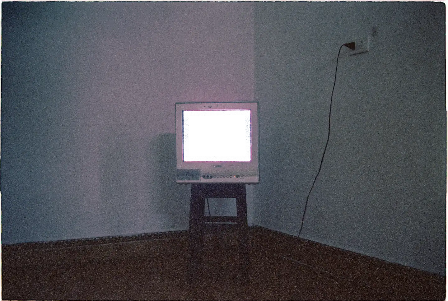 An old TV on a stool in the corner of an empty room